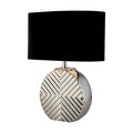 Regent chrome table lamp lit with a black shade above a geometric chevron mirrored base