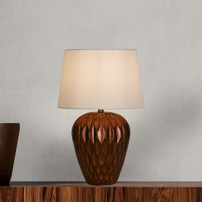 Rosetta bronze lamp lit on a wooden sideboard against a pale textured plaster wall