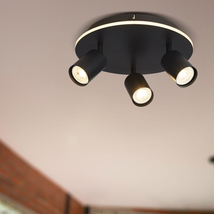 Ceiling-level view of the San Diego black spotlight plate lighting a room with brick wall