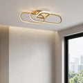 Modern gold LED flush ceiling light with interlaced oval loops mounted on a white ceiling.