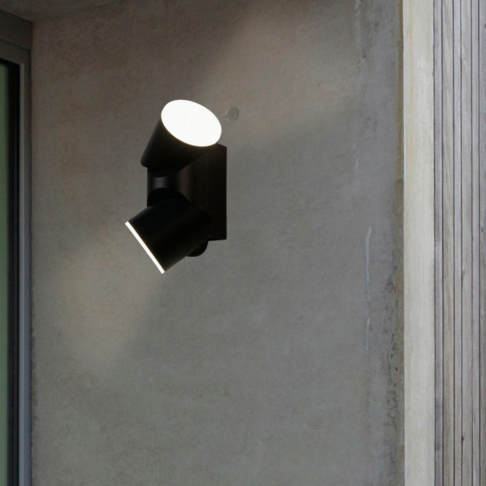 Soho black up and down wall light lit on a concrete exterior wall beside timber cladding