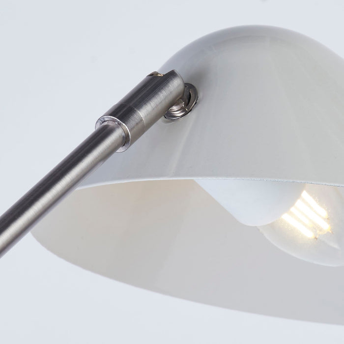 Close-up of the Swan lamp's white cone shade tilted on its brushed chrome curved neck