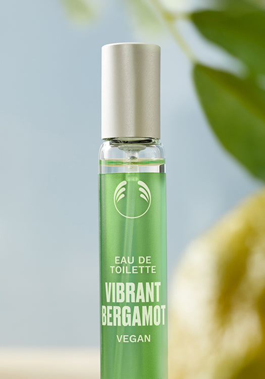 Green perfume bottle labeled 'Vibrant Bergamot' with a blurred background